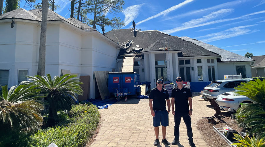 two First Light workers standing in front of home